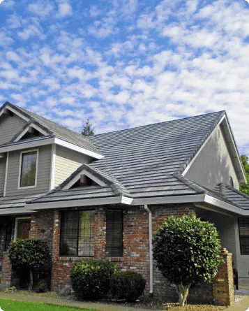 Modern two-story brick and siding house with solar panels under blue cloudy sky