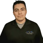 Professional headshot of young man in dark green polo shirt with company logo