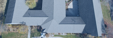 Aerial view of modern residential house with gray roof and driveway from above