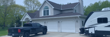 Modern two-story house with gray roof and white garage doors, black truck parked