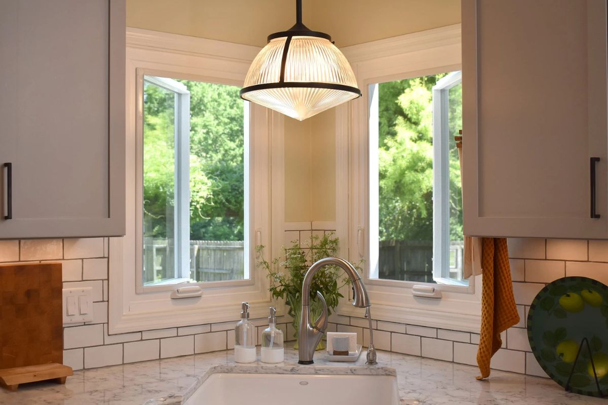 Modern kitchen corner sink with pendant light and white subway tile backsplash