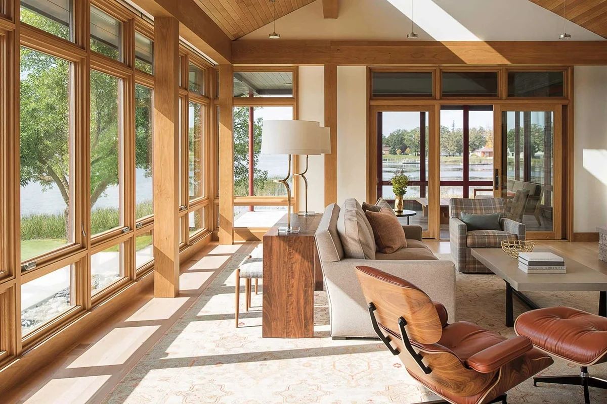 Modern lakehouse living room with wood beams, floor-to-ceiling windows and lake view