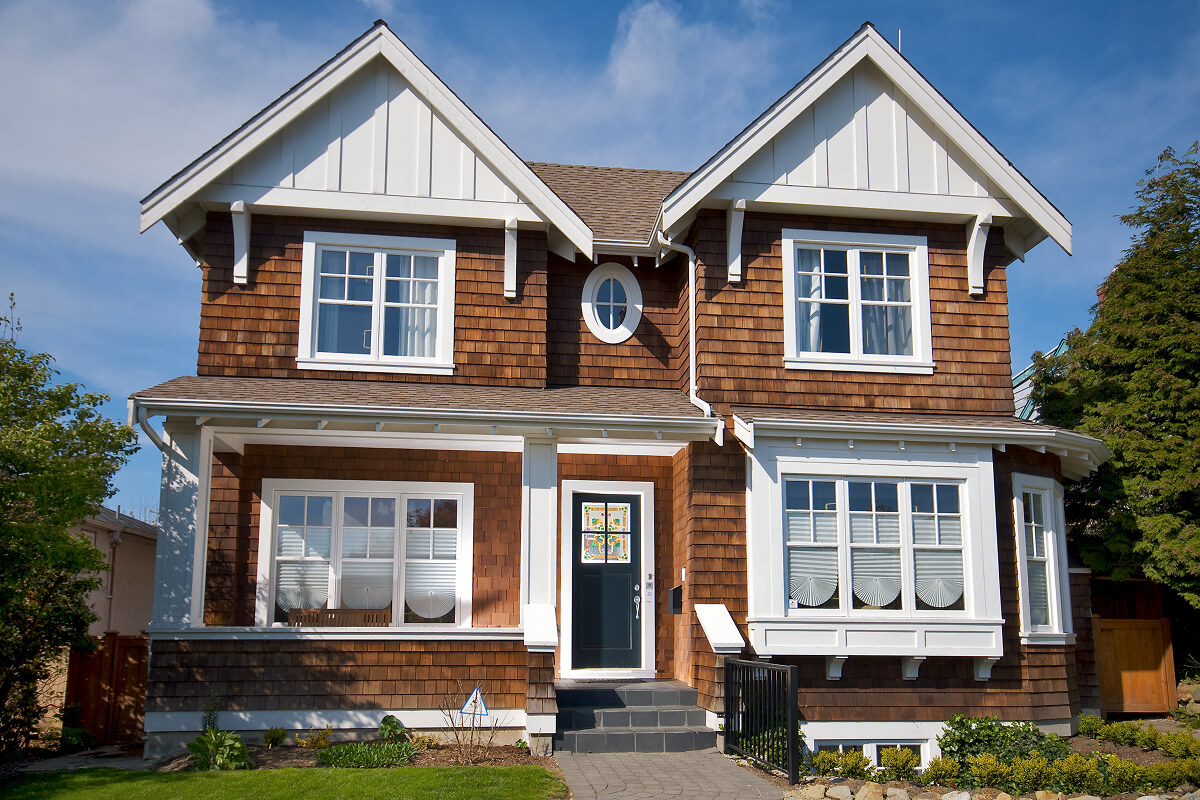 Charming two-story house with brown shingles and white trim in a suburban setting.