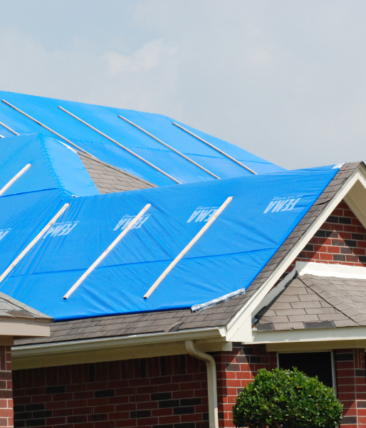 House roof covered with blue tarp protecting from weather damage.