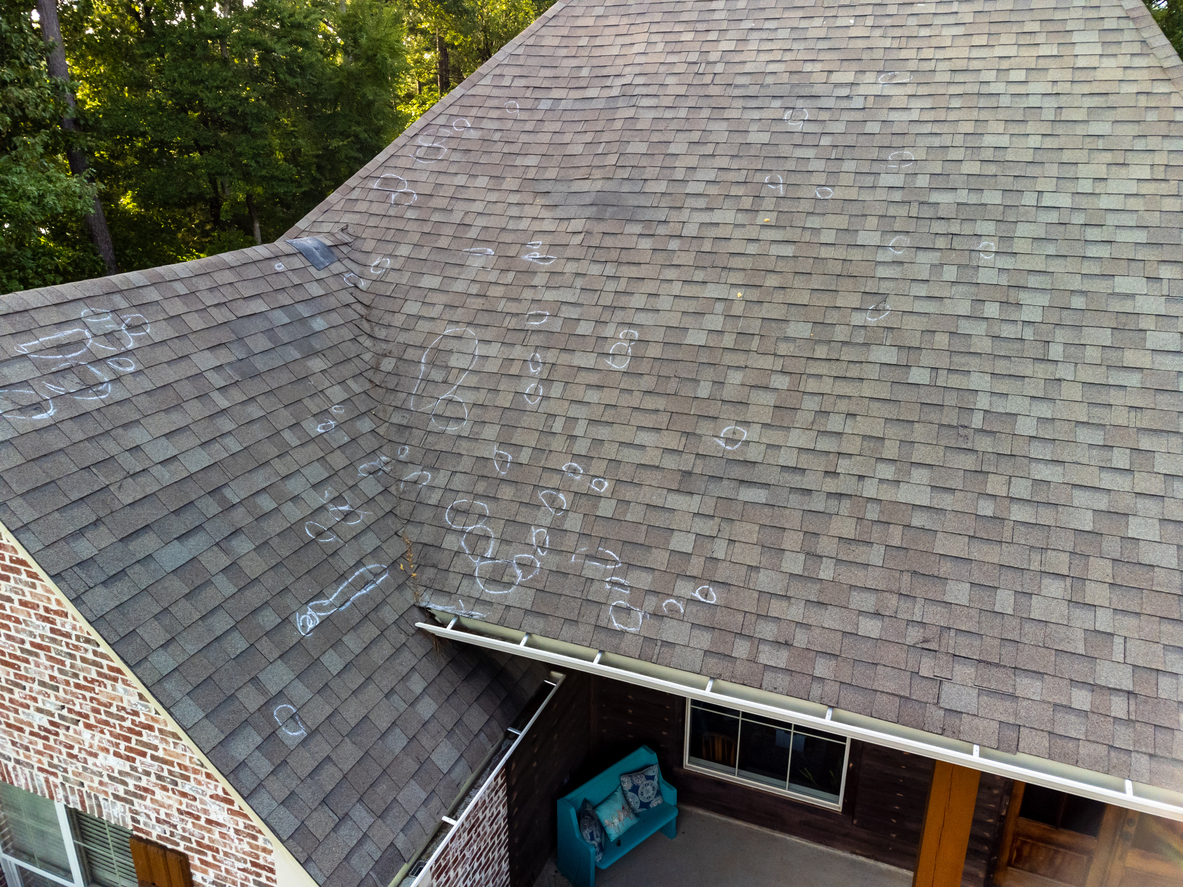 Aerial view of a house roof with chalk marks indicating repairs needed.