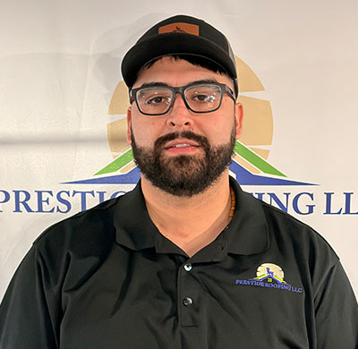 Man in black polo and cap with Prestige Roofing LLC logo.